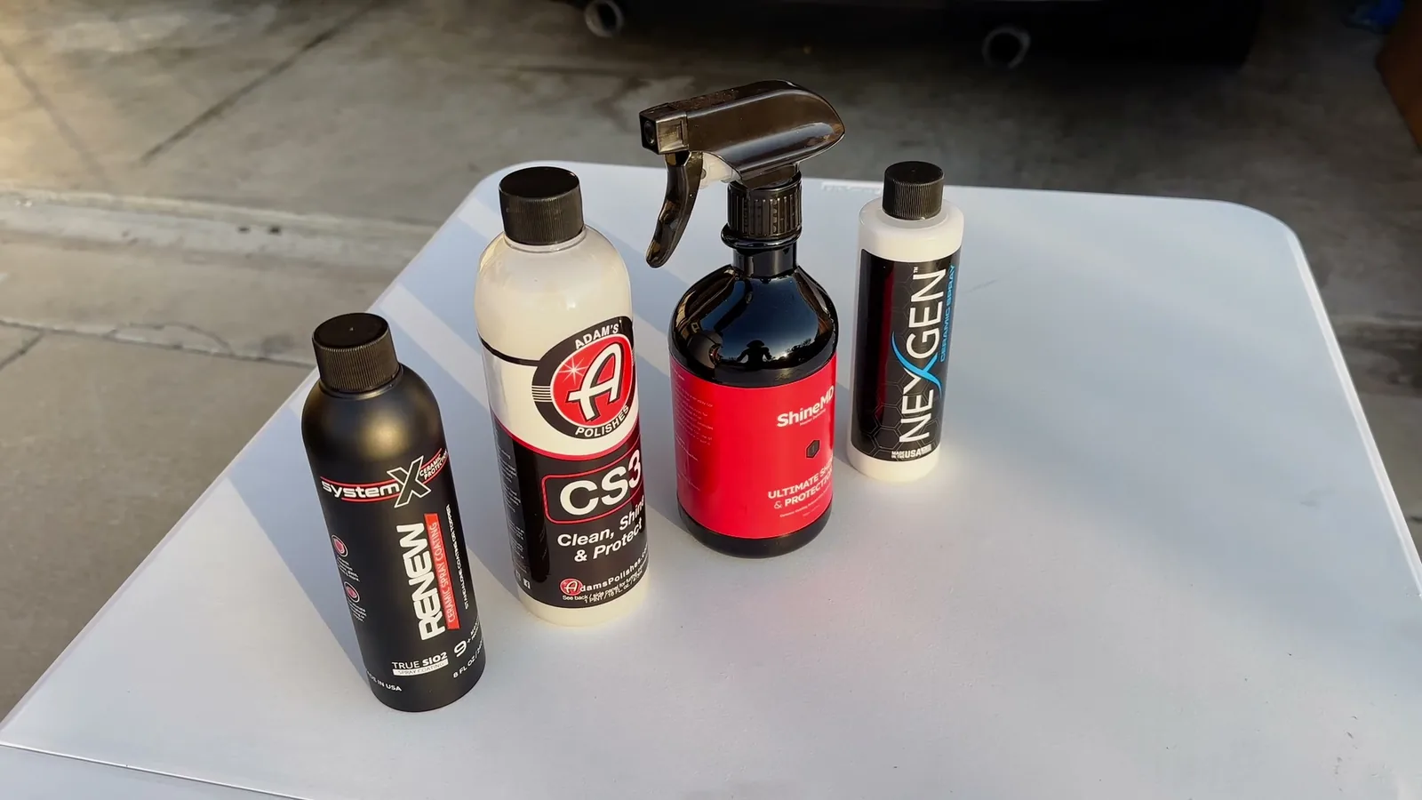 Four ceramic spray coating bottles from different brands lined up on a white table before a side-by-side comparison