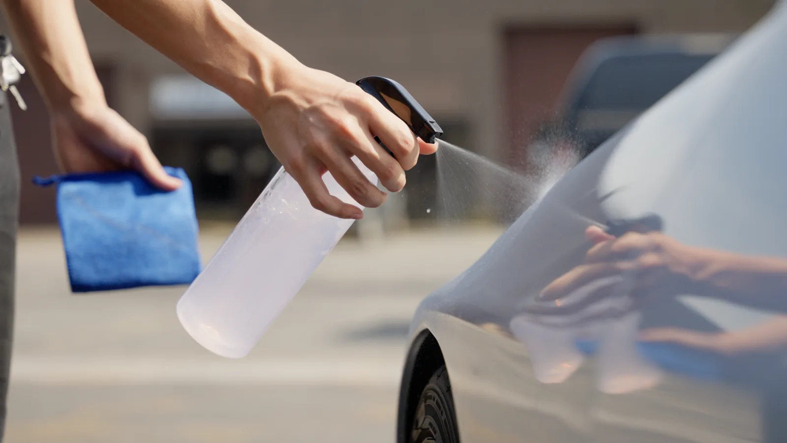 Spray mist hitting light paint beside a blue microfibre towel during outdoor application